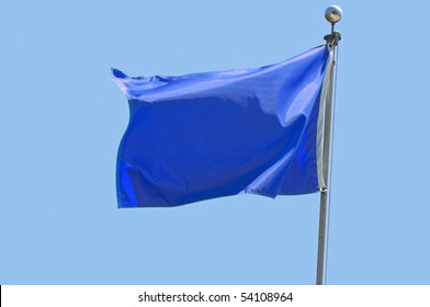 Blue Flag Flying In A Stiff Breeze Against A Clear Blue Sky.