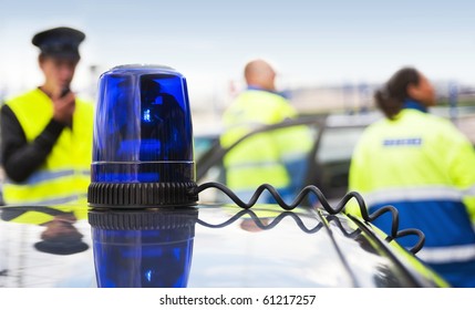 Blue Flashlight On Top Of An Unmarked Police Car, With A Team Of Emergency Medical Service Personnel In The Background