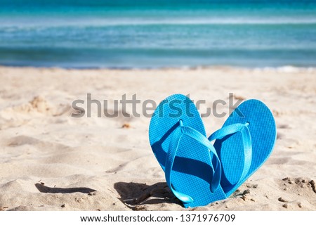 Blue flip flops on sand beach. Summer vacation concept
