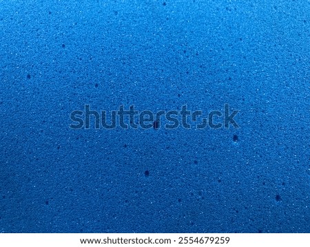 Blue foam surface with textured pattern. The surface appears to be made of porous material. The surface is consistent and appears to have a solid and uniform color. foam sponge With medium density