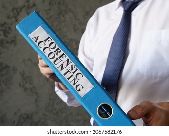 Blue Folder With Info About Forensic Accounting In The Hands.