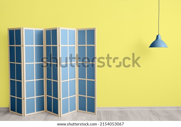 Blue folding screen near\
yellow wall