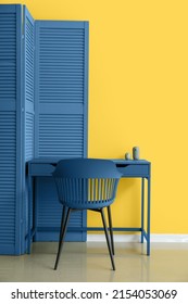 Blue Folding Screen, Table And Chair Near Yellow Wall