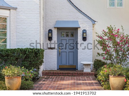 Blue front door of traditional style home with brick entry and white brick exterior.