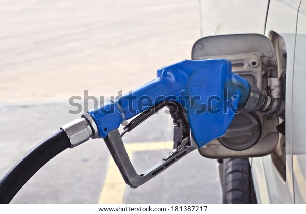 A blue fuel dispenser\
connecting to the car, add fuel, put in gasoline, benzene,\
diesel