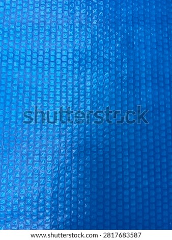 Blue geometric textured surface with repeating square pattern, abstract background