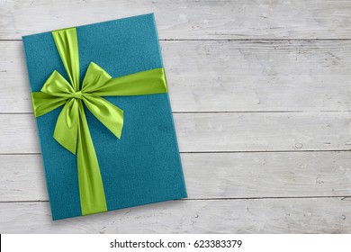 Blue Gift Box With Green Ribbon Over Light Wood, Top View From Above
