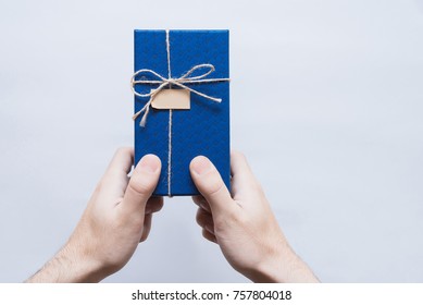 Blue Gift Box In Man Hands On A White Background. Gift For A Woman Gift Wrapping. Gift For A Business Porter In A Blue Box. Corporation. Corporate Style.