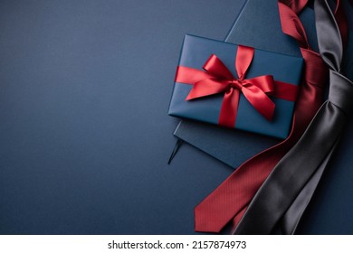 Blaue Geschenkbox, Notebook und Krawatten auf dunkelblauem Hintergrund. – Stockfoto