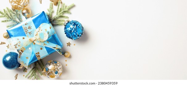 Blue gift box with ribbon bow, Xmas balls, fir branches isolated on white background with copy space. Christmas banner template.
