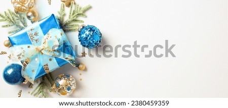 Blue gift box with ribbon bow, Xmas balls, fir branches isolated on white background with copy space. Christmas banner template.