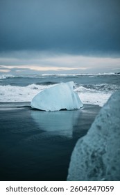 Blue glacial ice block reflected on wet black sand at Diamond Beach, South Iceland