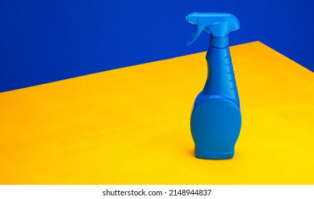 Blue Glass Cleaning Spray On A Yellow Table Against A Blue Background. The Concept Of Minimalism. Poster For Advertising. Place For Text
