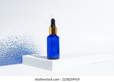 blue glass cosmetic bottle with a dropper on a white background with blue gradient. Natural cosmetics concept, natural essential oil and skin care products.