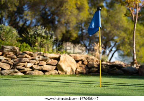 Blue golf\
flag on a miniature golf putting\
green