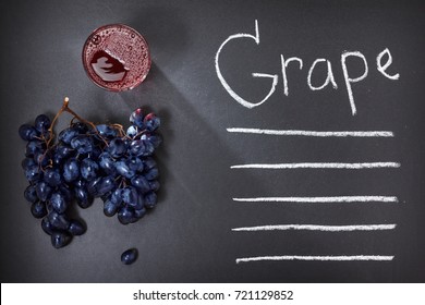 Blue Grape And Glass Of Juice Or Wine On Black Wooden Background Top View, With Copy Space.