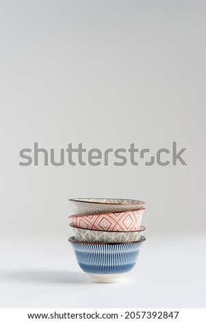 Blue, gray and red small ceramic empty bowls stacked on white background