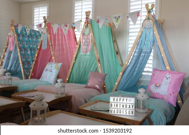 Blue, green, pink and lama teepee's all set up for a sleepover birthday party.  There is also fairy lights, bunting and face masks . 