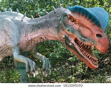 A blue, green, red and peach colored dinosaur with sharp teeth at Brookfield Zoo.