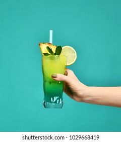 Blue And Green Tropical Alcohol Cocktail Drink With Pineapple In Woman Hand On Mint Background