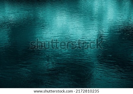    Blue green water surface. Night. Small waves. Ripples. Reflection of light. Dark teal water background with space for design.                            
