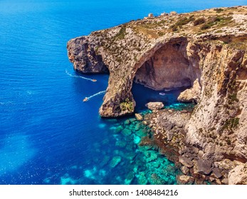 Blue Grotto in Malta. Pleasure boat with tourists runs. Natural arch window in the rock. Aerial top view