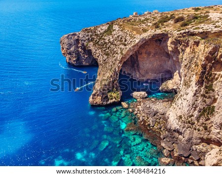 Blue Grotto in Malta. Pleasure boat with tourists runs. Natural arch window in the rock. Aerial top view
