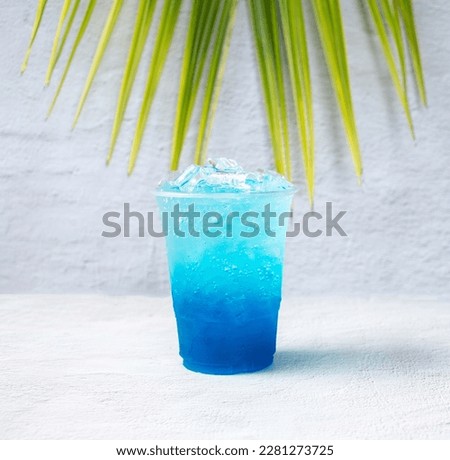 Blue Hawaiian drink in a plastic glass and coconut leaves.