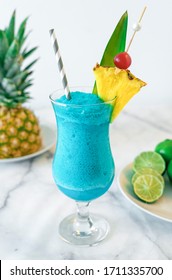 Blue Hawaiian Tropical Cocktail Drink Slush Mixed Blended With Pineapple Cherry And Lime On Marble Countertop Drink With Straw