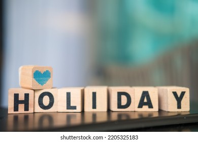 Blue Heart Icon Placed On Wooden Block Text Of Holiday For Campaign And Promotion. The Concept Of Off On Holiday And Planning A Holiday