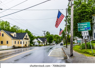 Blue Hill, USA - June 9, 2017: American Flag On City Main Street In Maine During Rainy Cloudy Weather With Directions