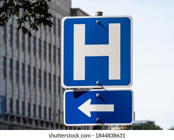 A Blue Hospital H Sign With An Arrow Pointing Left