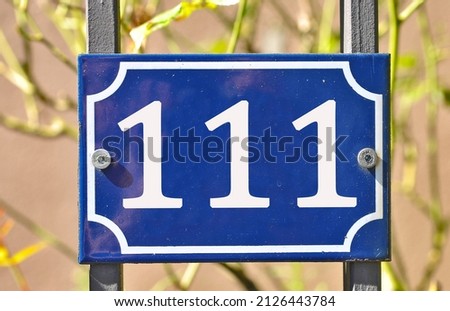 A blue house number plaque, showing the number hundred and eleven (111) 