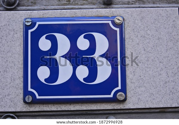 A blue house number plaque, showing the number\
thirty three (33)