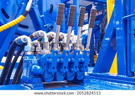 Blue hydraulic equipment close up. Levers for operating hydraulic equipment. Fragment of a blue hydraulic press. Machine tool for heavy industry. Concept - mechanical engineering.