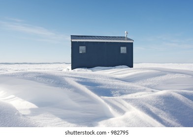 A Blue Ice Fishing Hut On A Frozen Lake During Winter.