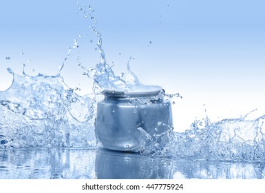 The blue jar of moisturizing cream in the big water splashes on the gradient blue background