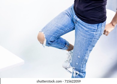 Blue jeans is create border shape. Casual style concept. Stylish woman wear skinny jeans and sneaker shoes sitting isolated on white background 
