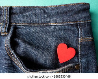 Blue jeans and one red heart lies in the back pocket of jeans on a green background - Powered by Shutterstock