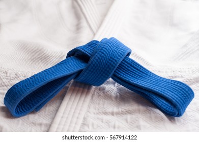 Blue judo, aikido or karate belt tied in a knot with white kimono in background - Powered by Shutterstock