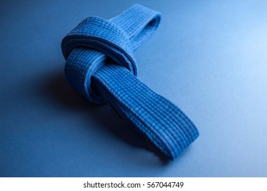 Blue Judo Belt Tied In A Knot Isolated On Blue Background