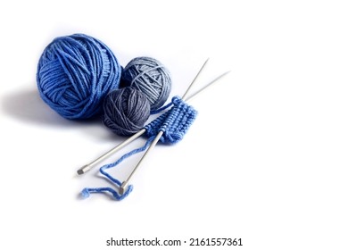 Blue knitted wool on a white background with knitting needles for knitting warm clothes, hobbies