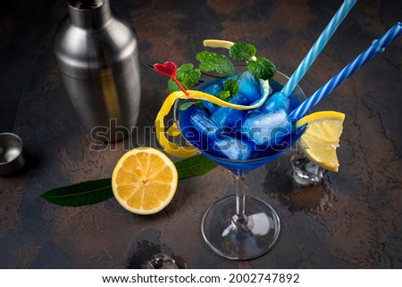 Blue lagoon cocktail with blue curacao liqueur, vodka, lemon juice and soda. Blue cocktail in martini glasses on black background. Copy space