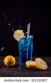 Blue Lagoon cocktail with lemon slices splash on black background