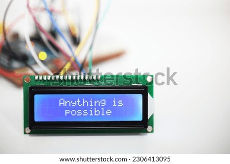 A blue LCD display showing the positive message 'Anything is possible' with wires coming from a computer circuit board in the background.