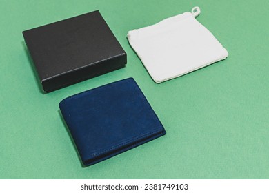 Blue leather money bag With a white cloth bag and packaging boxes Place on the green floor, package wallets, organize products, photograph products ready for sale. - Powered by Shutterstock