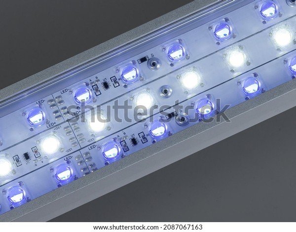 Blue LED flood light in aluminum housing with\
wire on dark background.