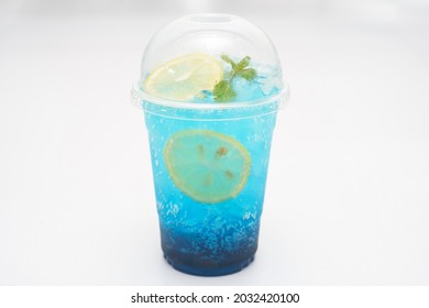 Blue Lemon Soda And Ice In A Plastic Cup Top With Sliced Lemon.