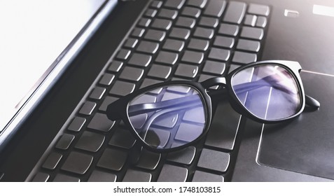 Blue Light Blocking Glasses On The Keyboard Button Of Computer Laptop. Working Or Learning Online.