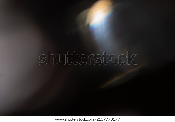 Blue light flare prism rainbow flares\
overlay effect on black background, light crossing crystals,\
prismatic sun catcher reflections rays. Abstract blurred colourful\
lens flare bokeh on dark\
backdrop